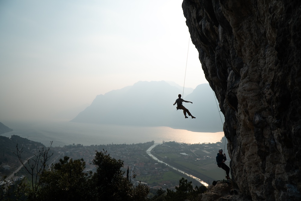 Julian hanging on a climbing rope over the garda lake in Belvedere near Arco.